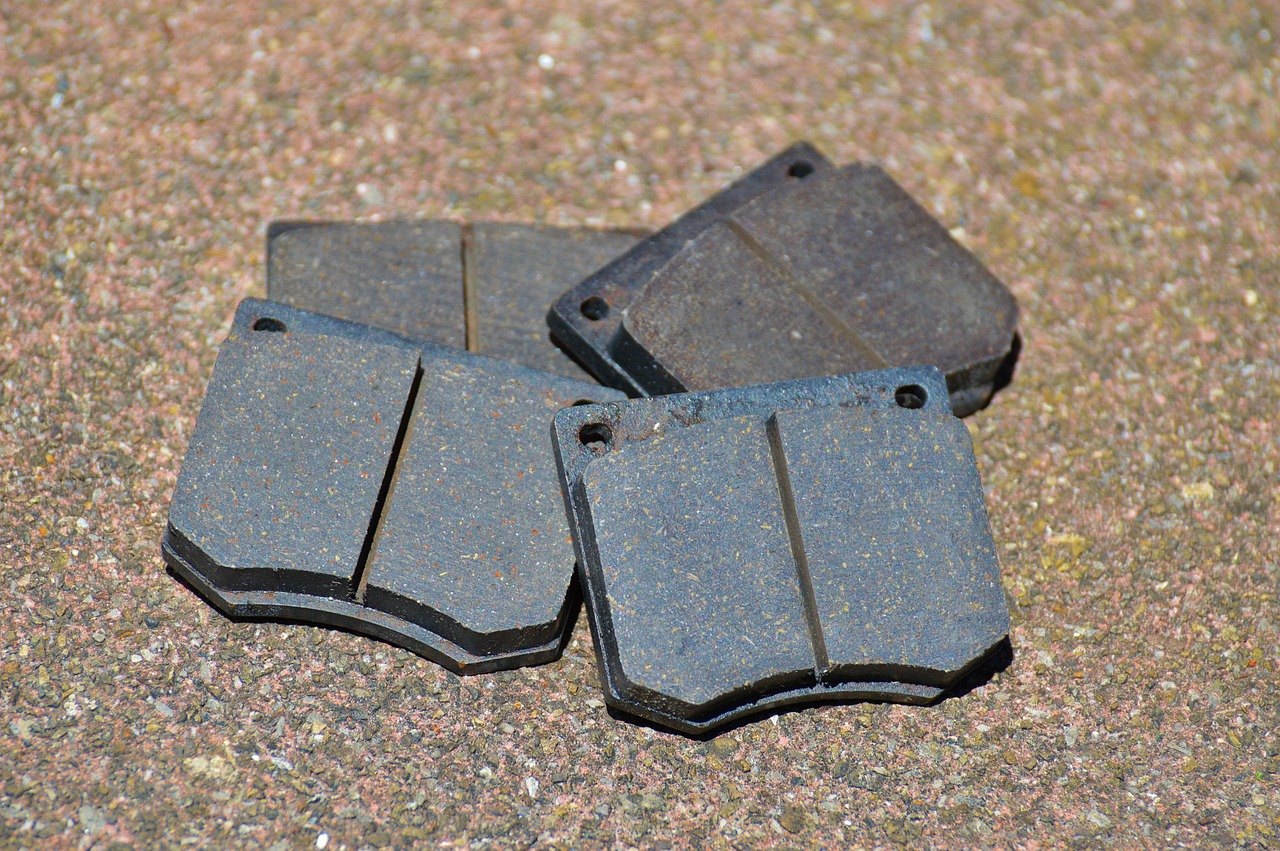 Four disc brake pads lying on the ground, with their friction material facing up