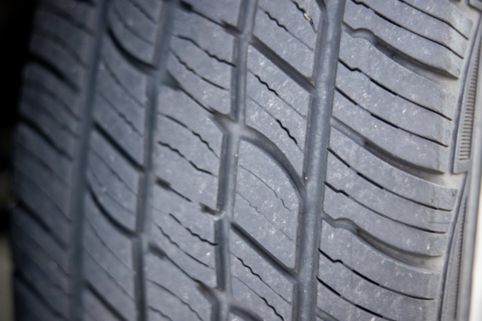 Close-up of a car tyre's tread, showing the wide grooves that run around it and the tread blocks between them